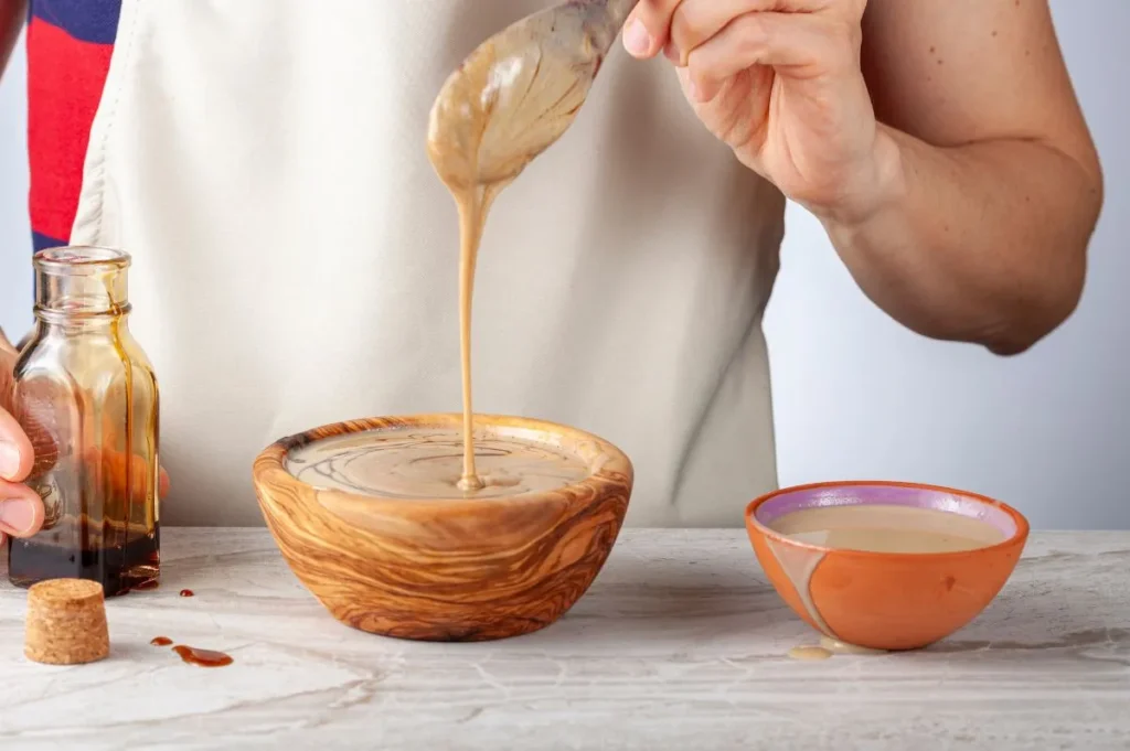 Mujer preparando una salsa con pasta de sésamo o tahín ecológico.